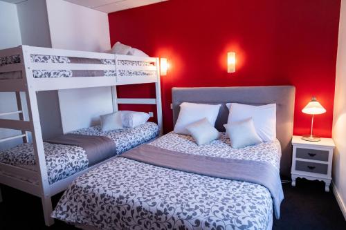 a bedroom with two bunk beds and a red wall at Hotel Henri IV in Sully-sur-Loire