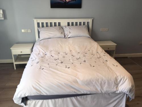 uma cama com um edredão branco com flores em Swans Nest em Holmfirth