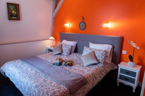 a bedroom with a bed with an orange wall at Hotel Henri IV in Sully-sur-Loire