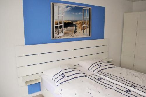 ein Schlafzimmer mit einem weißen Bett und einem Spiegel darüber in der Unterkunft Wohnung "Föhr" - Haus Dünengras in Büsum