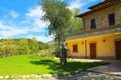 a yellow house with a tree in the yard at Antica Fonte in Assisi