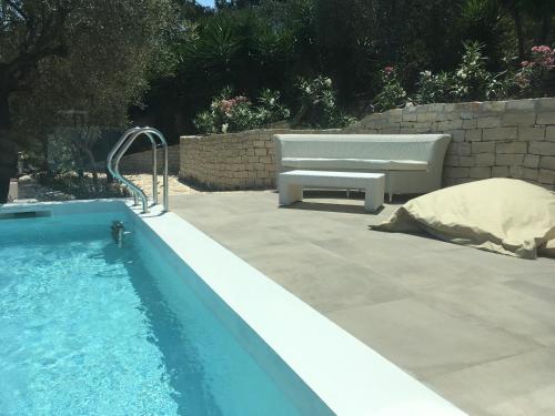 a swimming pool next to a bench and a bench at Viestemare Resort & SPA in Vieste