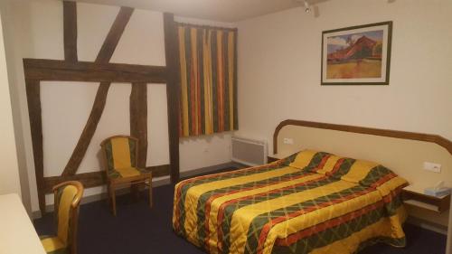 ein Schlafzimmer mit einem Bett, einem Tisch und einem Stuhl in der Unterkunft Le Cheval Rouge in Louhans