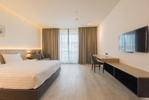 Habitación de hotel con cama, escritorio y TV. en Madison Bangkok Hotel, en Bangkok