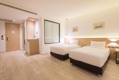 a hotel room with two beds and a mirror at Madison Bangkok Hotel in Bangkok