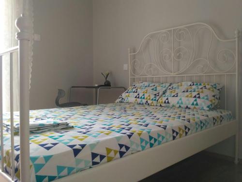 a bedroom with a white bed with a colorful comforter at Little Romantic Appartment in Agrinio