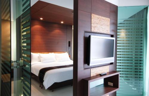 a hotel room with a bed and a flat screen tv at Tara Mantra Cha-Am Resort in Cha Am