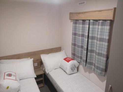 um pequeno quarto com 2 camas e uma janela em Tattershall Lakes 2020 8 Berth Caravan With Hot Tub em Tattershall