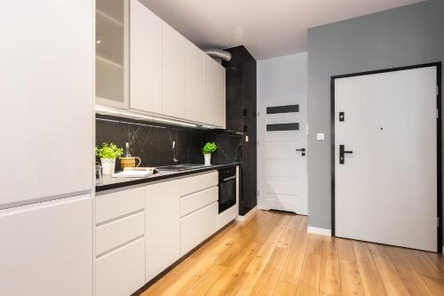 a kitchen with white cabinets and a wooden floor at NOVUM Apartment in Krakow