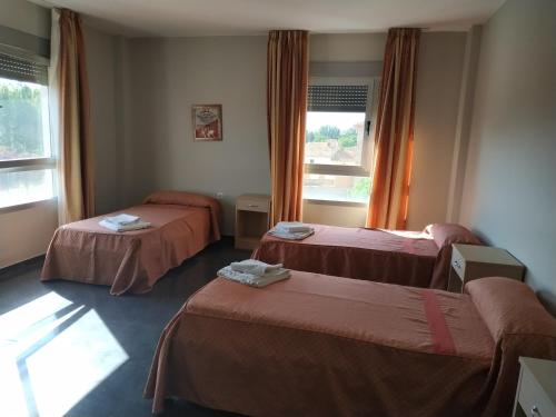 Cette chambre comprend trois lits et deux fenêtres. dans l'établissement Hostal restaurante la concordia, à Fuentes Claras