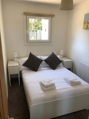a bedroom with a white bed with two tables and a window at Premium Lake Lodges in Chichester