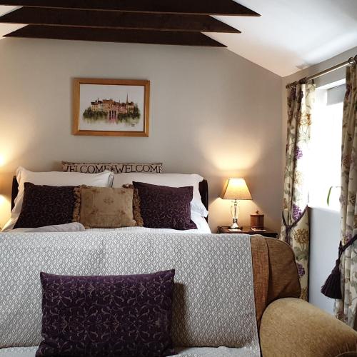 a bedroom with a large bed and a couch at The Nest at Bramble Cottage Lacock in Lacock