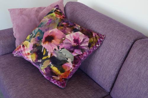 a colorful pillow sitting on a purple couch at Appartementen de Strandloper in Bergen aan Zee