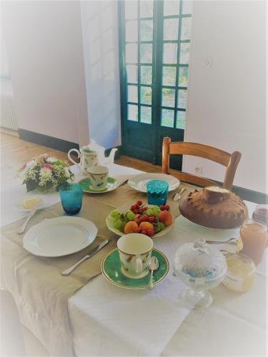 a table with plates and cups and fruit on it at Maison du Moulin in Donzy