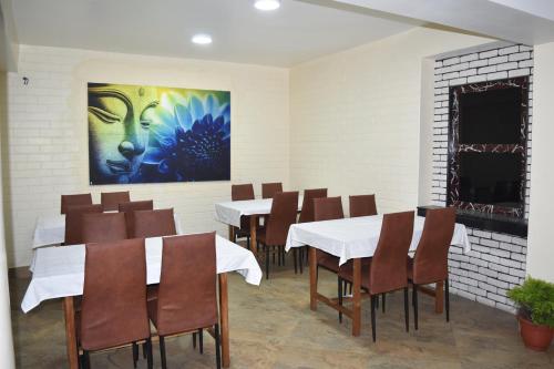 a dining room with tables and chairs and a painting at Amba Regency in Gangtok