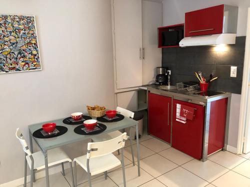 a small kitchen with a table and chairs with red cabinets at Brive Centre in Brive-la-Gaillarde
