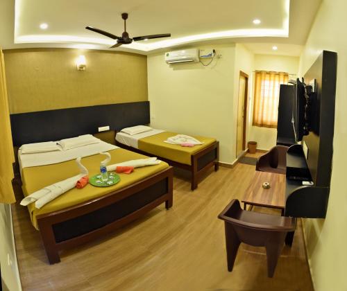 a small room with two beds and a table at Siva Residency in Mahabalipuram