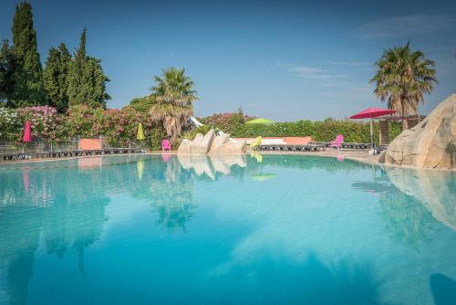 une grande piscine d'eau avec des palmiers en arrière-plan dans l'établissement Camping Le Méditerranée Argelès - Domaine piétonnier, à Argelès-sur-Mer
