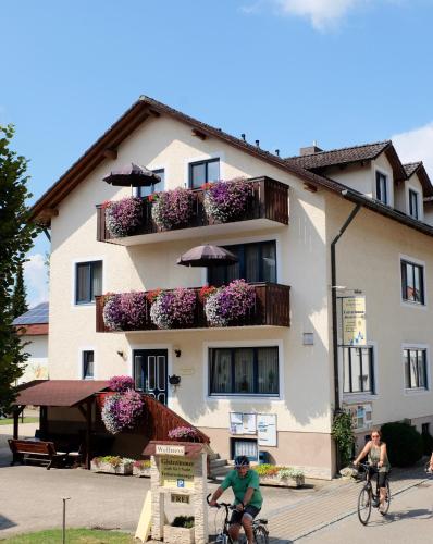 two people riding bikes in front of a building at Gästehaus Biedermann in Kinding