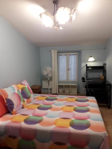 une chambre avec un grand lit avec une couverture colorée dans l'établissement Maison de village, à Bagnols-en-Forêt