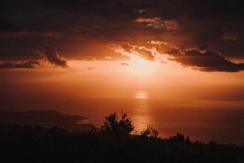 a sunset over the ocean with the sun in the sky at Ferme l'Eau de Coco in Saint-Paul