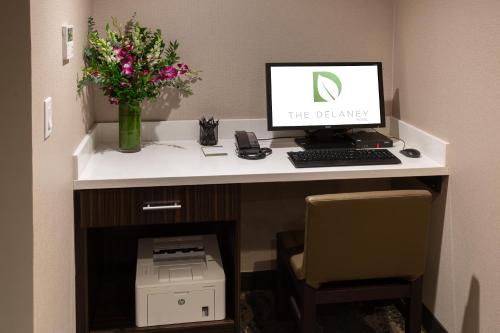 a desk with a computer and flowers on it at The Delaney Hotel in Orlando