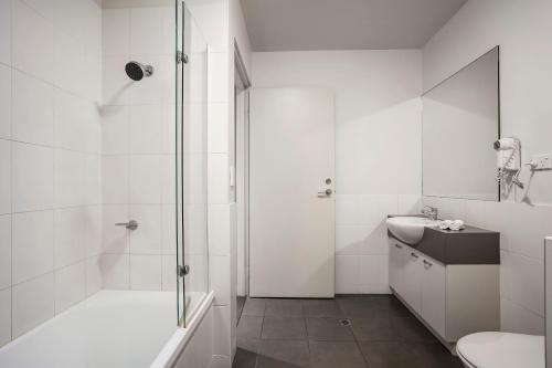 a white bathroom with a shower and a sink at Quest Alice Springs in Alice Springs