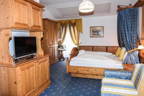 a bedroom with a bed and a flat screen tv at Hotel Relais Grünwald in Cavalese