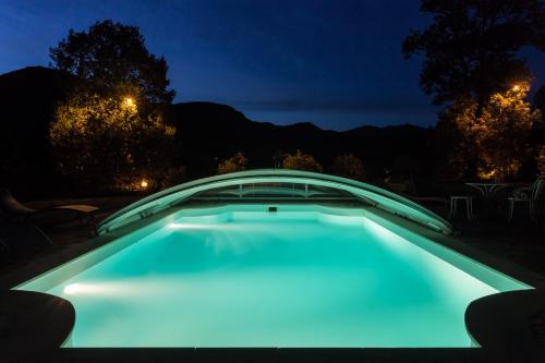 a swimming pool lit up at night with a bridge at Le Kino Panorama in Vic-sur-Cère