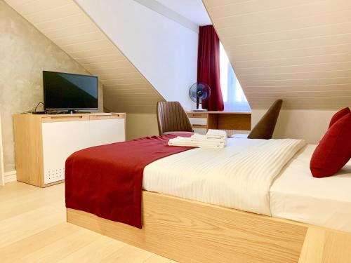 a bedroom with a bed and a television in a attic at Hotel Adore in Romanel-sur-Lausanne