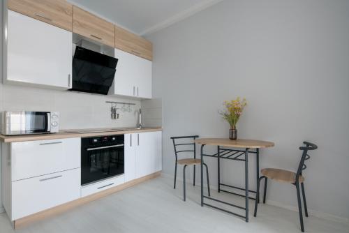 a kitchen with white cabinets and a table and chairs at Comfort House in Kyiv