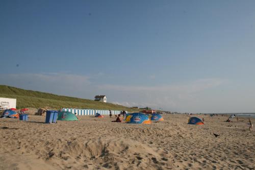 a group of people on a beach with tents at Appartementen de Strandloper in Bergen aan Zee