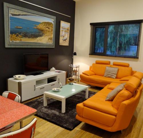 a living room with an orange couch and a tv at The Gallery Accommodation McCrae in McCrae