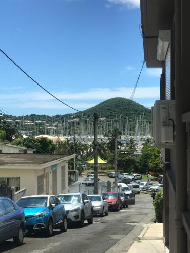 a street filled with parked cars with a marina at Arôme Marin in Le Marin
