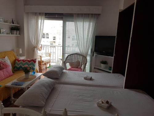 um quarto com 2 camas e uma sala de estar com uma janela em Atico estudio en 1°linea Almuñecar em Almuñécar
