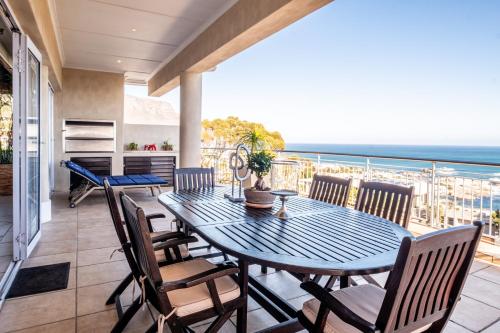 un comedor con mesa y sillas y el océano en 3 On Camps Bay, en Ciudad del Cabo