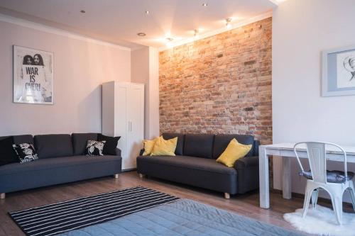 una sala de estar con 2 sofás y una pared de ladrillo en Big Apartment - City Center - 70m2 - Nice Design, en Wroclaw