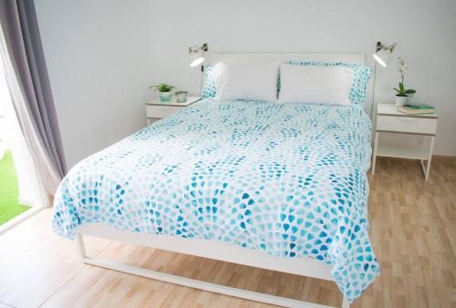 a bed with a blue and white comforter at Steps to the beach!!! in Santa Cruz de Tenerife