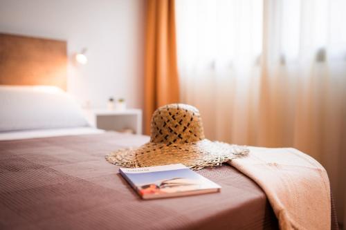 un sombrero de paja encima de una cama con un libro en Lindala, en Valencia