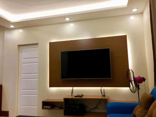 Arcadio's Guest House in Mactan, Cebu في مدينة سيبو: غرفة معيشة فيها تلفزيون على جدار