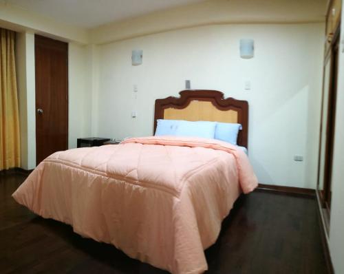 a bedroom with a large bed with a pink blanket at Hotel Panamericano in Lima