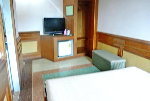 a room with a tv and a couch and a chair at Rose Garden Hotel in Phra Nakhon Si Ayutthaya