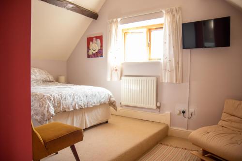 um quarto com uma cama, uma janela e uma cadeira em Churchlands em Bromyard