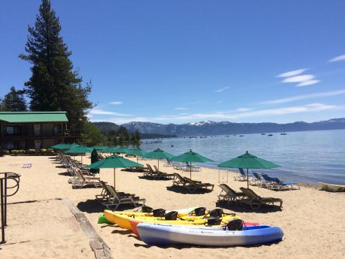 ein Strand mit Stühlen, Sonnenschirmen und Booten darauf in der Unterkunft Mourelatos Lakeshore Resort in Tahoe Vista