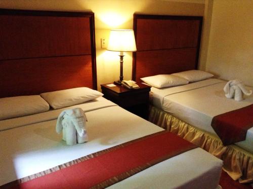 a hotel room with two beds with towels on them at Crown Regency Residences Davao in Davao City