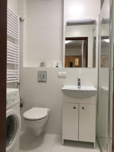 een witte badkamer met een wastafel en een wasmachine bij Anita Apartament Nowowiejska in Warschau