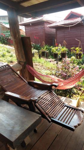 a hammock sitting on a wooden deck with a table at Ratanak Tep Rithea homestay in Banlung