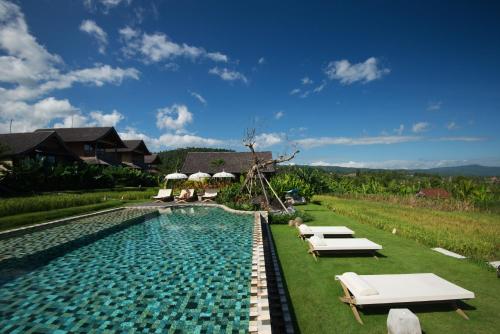 a swimming pool with lounge chairs next to a house at Sanak Retreat Bali in Munduk