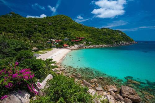 a beach with a bunch of flowers and the ocean at Chabalay Resort in Koh Tao