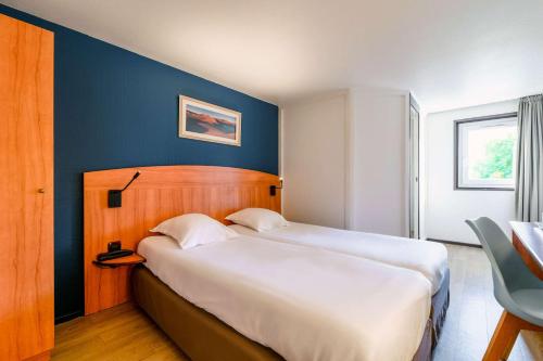 a bedroom with a large bed with a blue wall at Comfort Hotel Evreux in Évreux